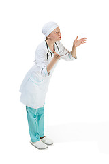 Image showing Beautiful young woman is sending an air kiss in white coat posing at studio. Full length studio shot isolated on white.