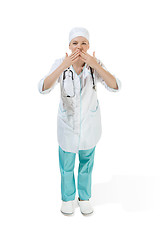 Image showing Beautiful young woman is sending an air kiss in white coat posing at studio. Full length studio shot isolated on white.