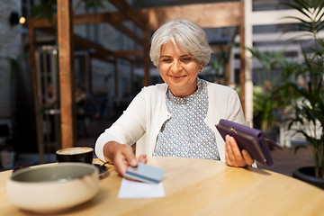 Image showing senior woman with credit card paying bill at cafe