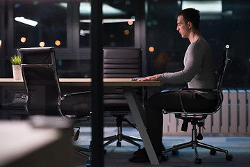 Image showing man working on laptop in dark office