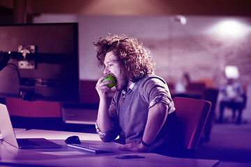 Image showing man eating apple in his office