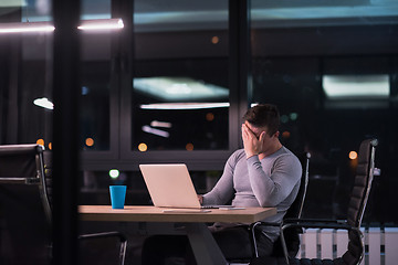 Image showing man working on laptop in dark office