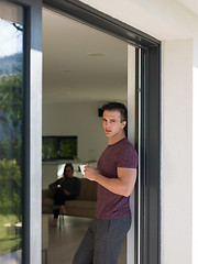 Image showing man drinking coffee in front of her luxury home villa