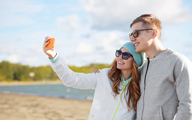 Image showing happy teenage couple taking selfie by smartphone