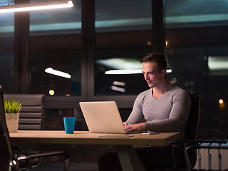 Image showing man working on laptop in dark office