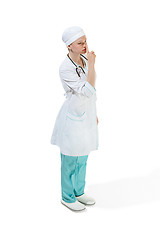 Image showing Beautiful young woman is whispering a secret in white coat posing at studio. Full length studio shot isolated on white.