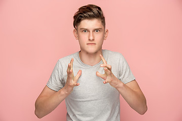 Image showing The young emotional angry man screaming on pink studio background