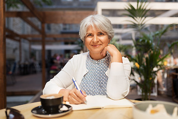 Image showing senior woman with notebook and coffee at cafe