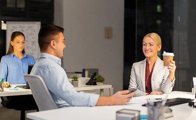 Image showing business people drinking coffee at night office