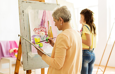 Image showing senior woman painting at art school studio
