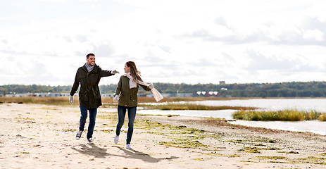 Image showing couple running along autumn beach