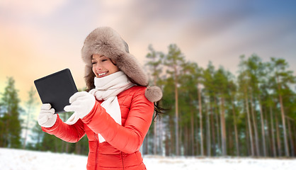 Image showing woman in fur hat with tablet pc over winter forest