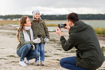 Image showing family photographing by smartphone on autumn beach