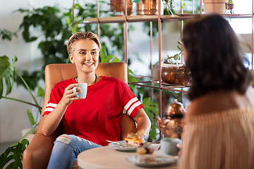 Image showing female friends drinking coffee and talking at cafe
