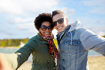 Image showing happy teenage couple taking selfie over beach
