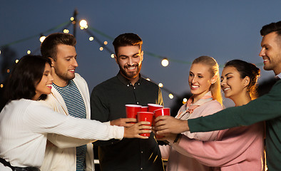 Image showing friends clinking party cups on rooftop at night