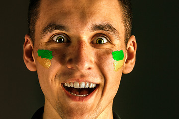 Image showing Portrait of a man with the flag of the Brazil painted on him face.