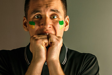 Image showing Portrait of a man with the flag of the Brazil painted on him face.