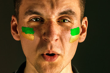 Image showing Portrait of a man with the flag of the Brazil painted on him face.