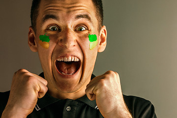 Image showing Portrait of a man with the flag of the Brazil painted on him face.