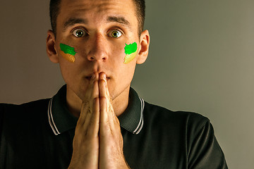 Image showing Portrait of a man with the flag of the Brazil painted on him face.