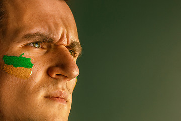 Image showing Portrait of a man with the flag of the Brazil painted on him face.