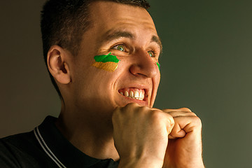 Image showing Portrait of a man with the flag of the Brazil painted on him face.