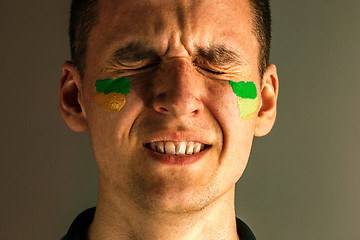 Image showing Portrait of a man with the flag of the Brazil painted on him face.