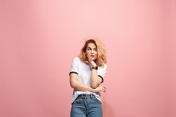 Image showing The young woman whispering a secret behind her hand over pink background