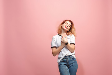 Image showing The happy business woman is smiling and keeping in hand the smartphone against pink background.