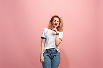 Image showing The young woman whispering a secret behind her hand over pink background