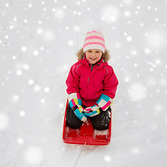 Image showing happy girl riding sled on snow in winter