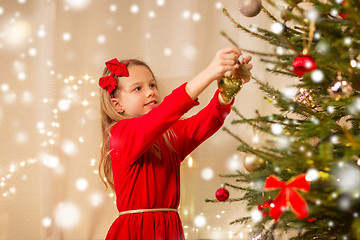 Image showing happy girl in red dress decorating christmas tree