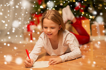 Image showing smiling girl writing christmas wish list at home