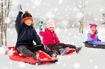 Image showing happy little kids sliding on sleds in winter