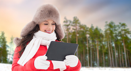 Image showing woman in fur hat with tablet pc over winter forest