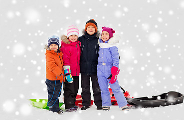 Image showing happy little kids with sleds hugging in winter