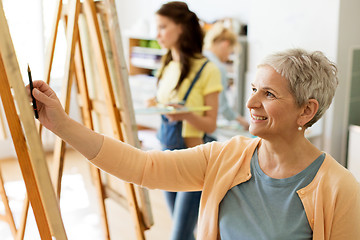 Image showing senior woman drawing on easel at art school studio