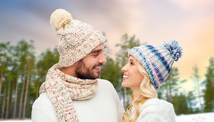 Image showing happy couple in hats over winter forest background