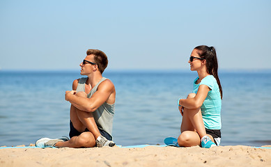 Image showing smiling couple stretching legs on beach