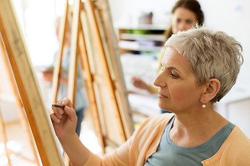 Image showing senior woman drawing on easel at art school studio