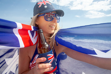 Image showing Australian woman holding a flag and beer bottle celebrating Aust