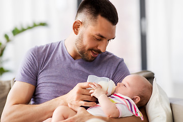 Image showing father feeding baby daughter from bottle at home