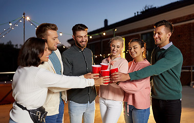 Image showing friends clinking party cups on rooftop at night