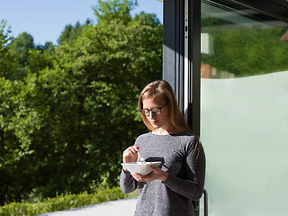 Image showing woman eating breakfast in front of her luxury home villa