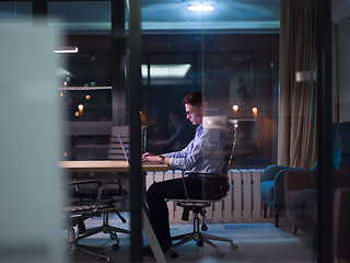 Image showing man working on laptop in dark office