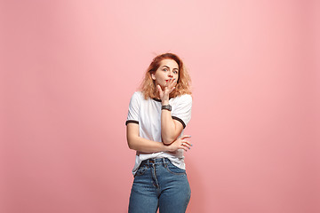 Image showing The young woman whispering a secret behind her hand over pink background