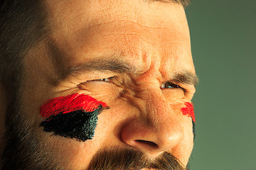 Image showing Portrait of a man with the flag of the Germany painted on him face.