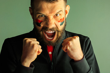 Image showing Portrait of a man with the flag of the Germany painted on him face.