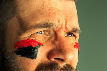 Image showing Portrait of a man with the flag of the Germany painted on him face.